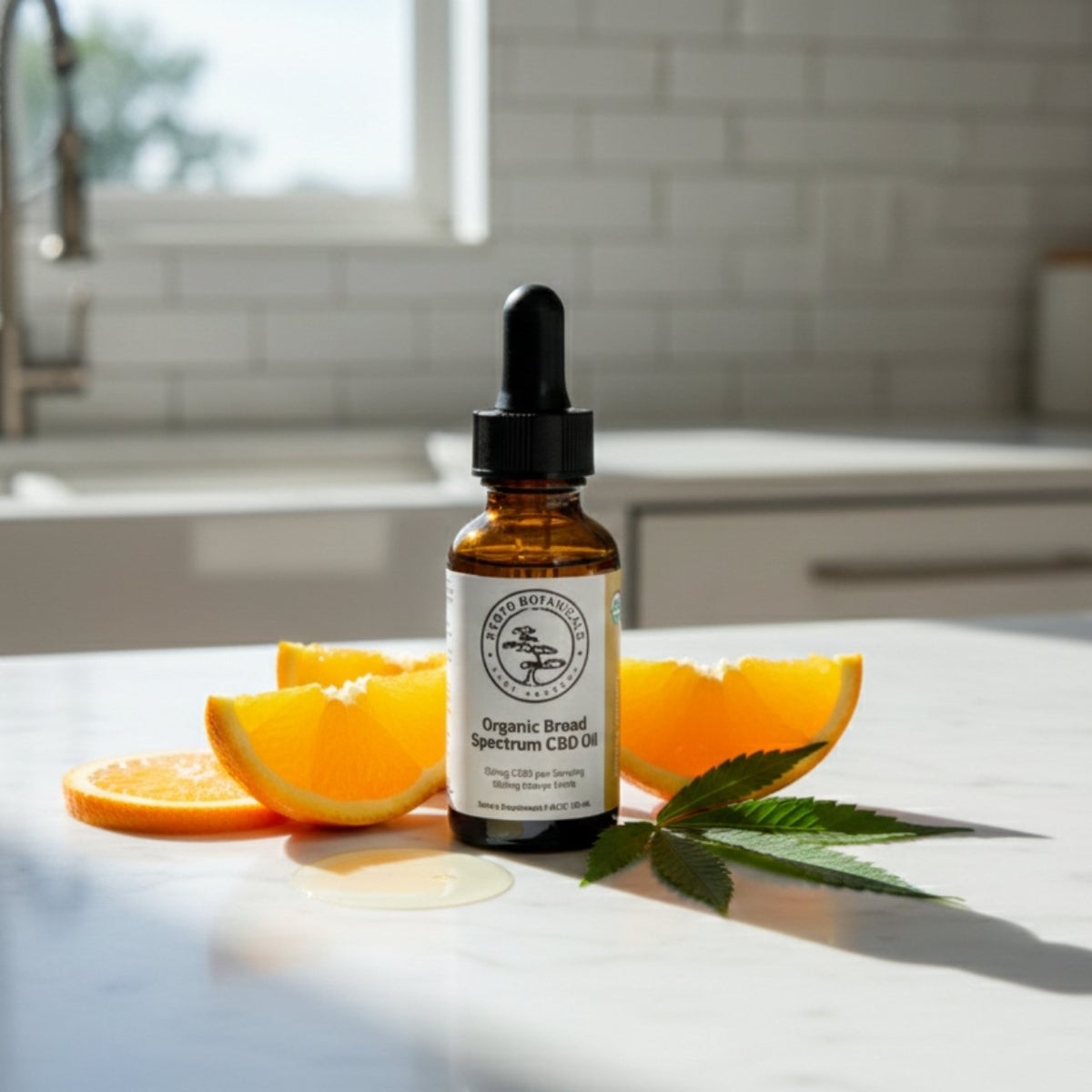 Kyoto Botanicals Organic THC-Free Orange CBD Tincture bottle on a white marble kitchen counter with fresh orange slices and hemp ingredients.